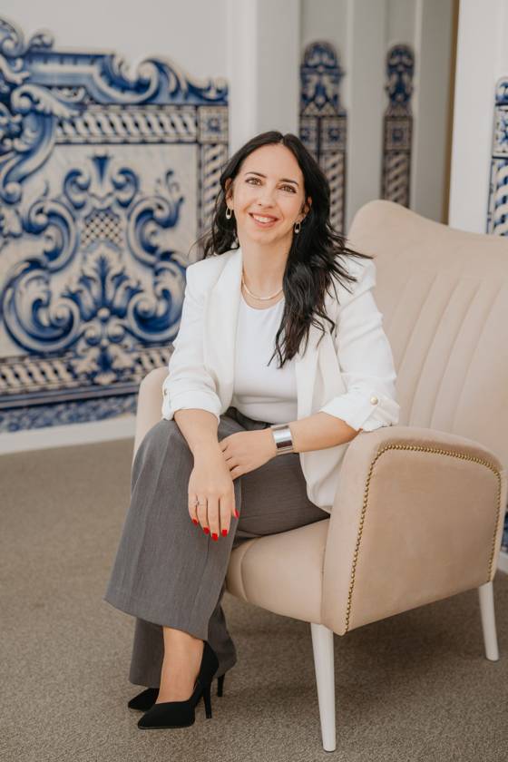 Joana Gomes, Contabilista Certificada, sentada num cadeirão em frente a um painel de azulejos azuis